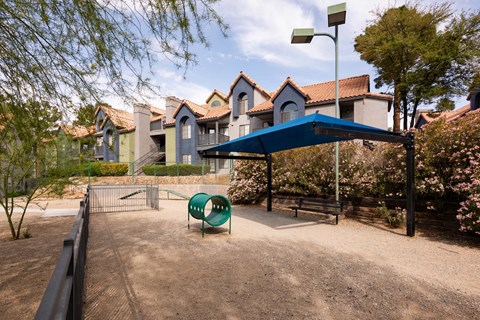 a park with a playground and a blue canopy