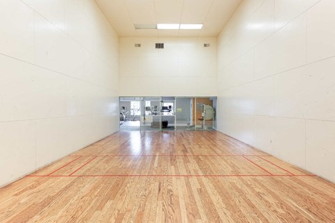 a large room with a racquetball court and a wooden floor