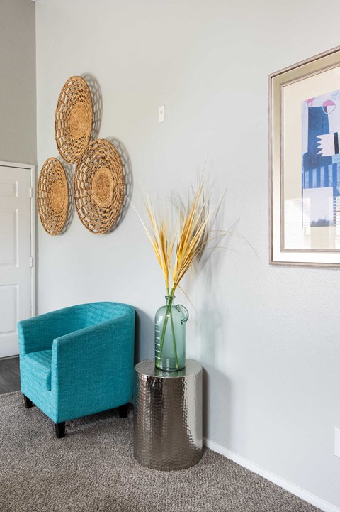 a living room with a blue chair and a vase