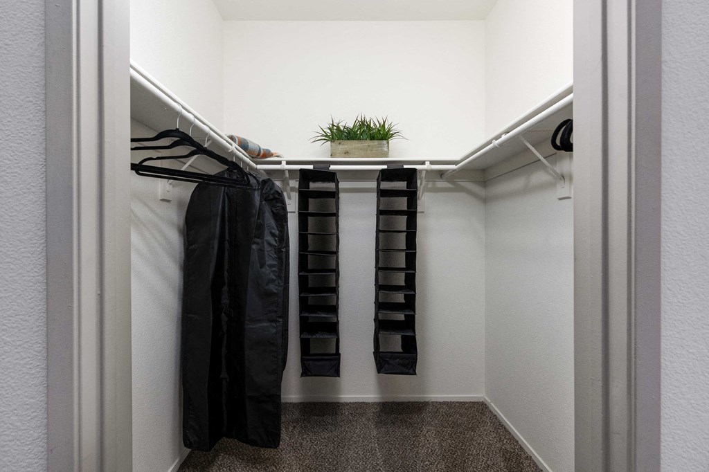 a walk in closet with robes and a plant in it