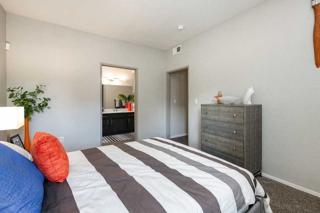 a bedroom with a bed and a dresser and a bathroom