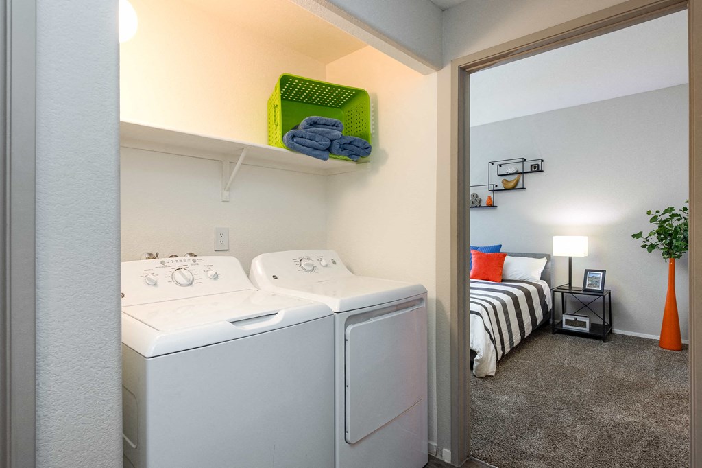 a laundry room with a washer and dryer and a bedroom with a bed