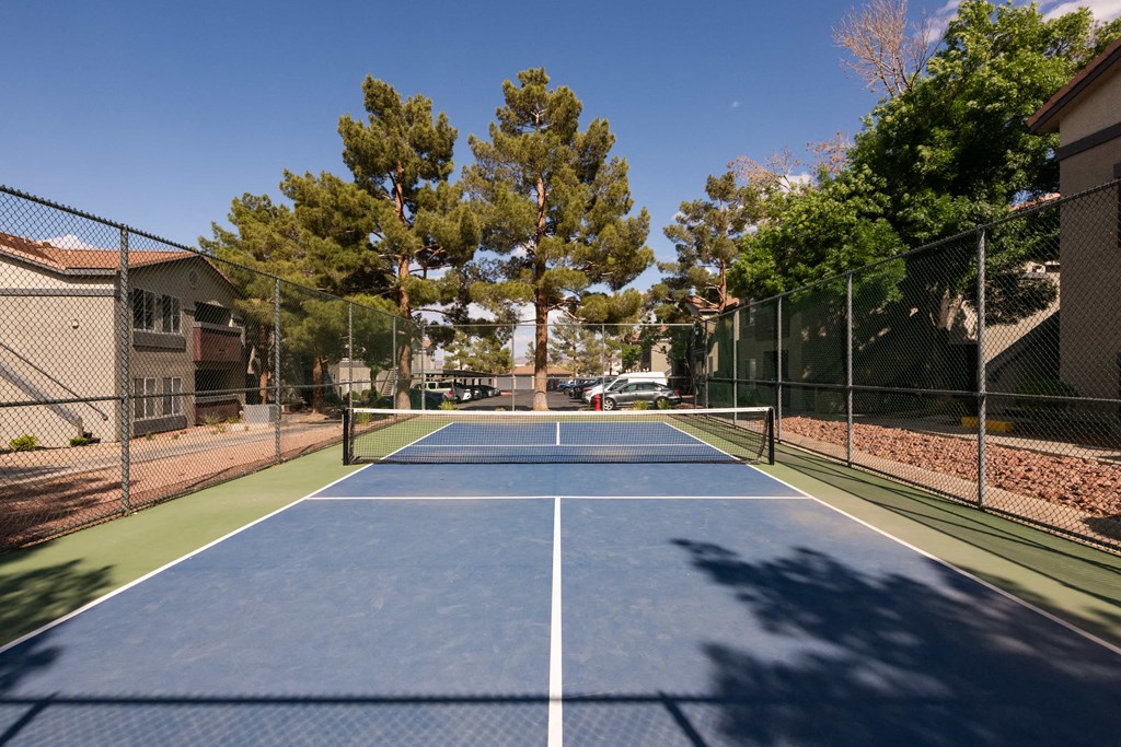 a tennis court with a fence around it and trees