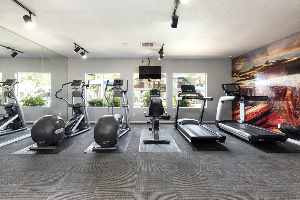 a gym with cardio equipment and a painting on the wall