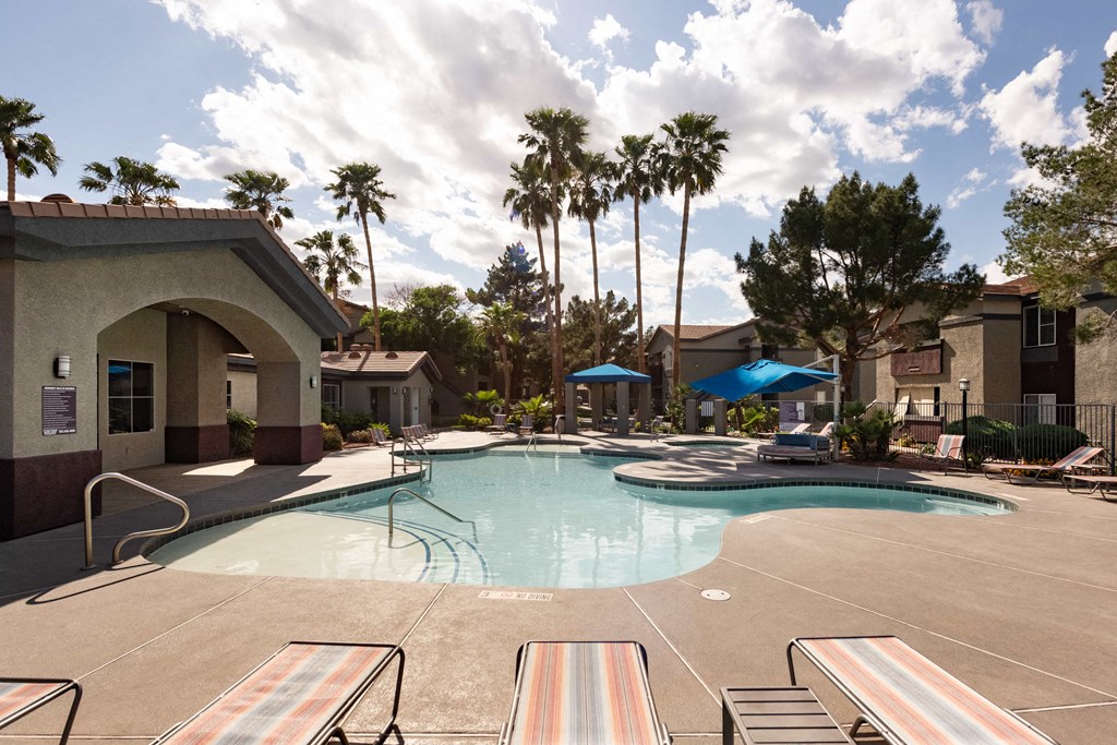 a large swimming pool with palm trees in the background