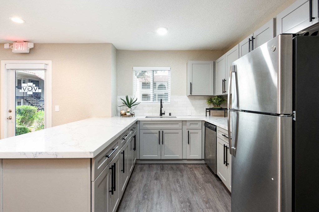 a kitchen with white cabinets and a stainless steel refrigerator