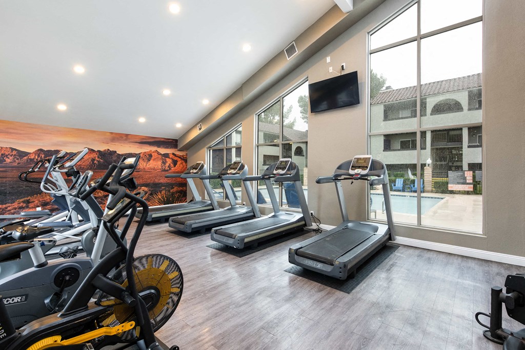 a gym with cardio equipment and a window view of a swimming pool