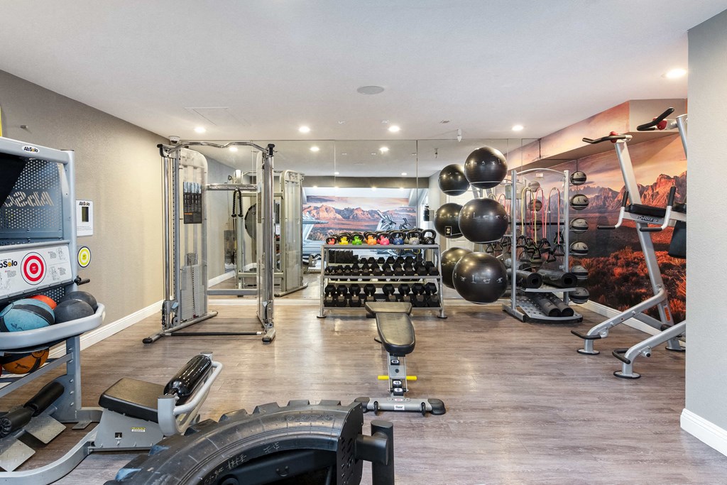 a home gym with weights and cardio equipment and a wall mural