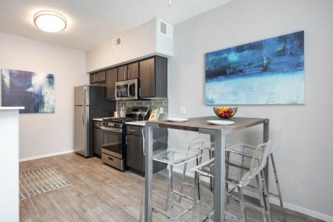 a kitchen with a bar with stools and a stainless steel refrigerator