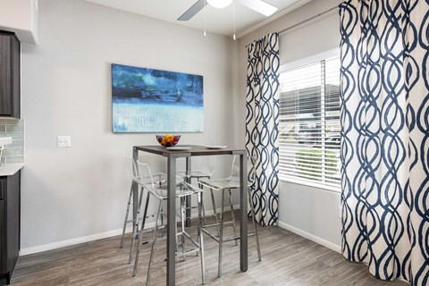 a bar area with stools and a table with chairs in front of a window