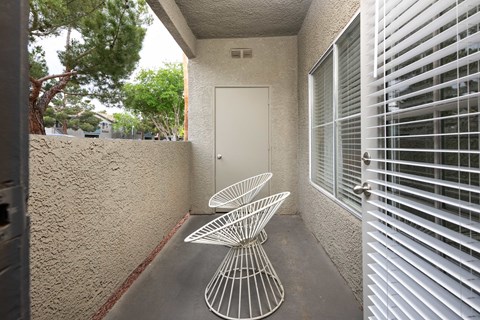 a patio with two chairs and a table in front of a door