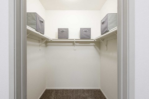 a walk in closet in a home with white walls and shelves