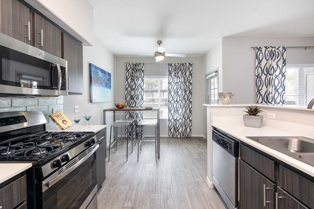 a kitchen with stainless steel appliances and a dining room with a table and chairs