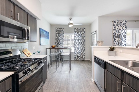 a kitchen with stainless steel appliances and a dining room with a table and chairs