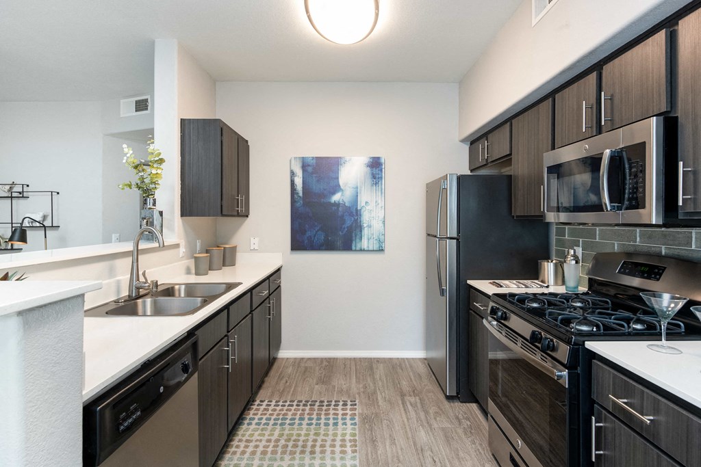 an empty kitchen with stainless steel appliances and wood flooring