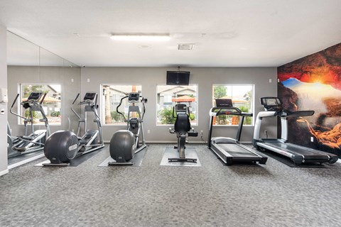 a gym with treadmills and other exercise equipment in a building with windows