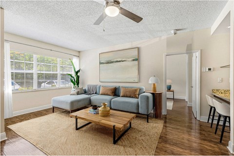A living room with a grey couch, a wooden coffee table, and a painting on the wall.
