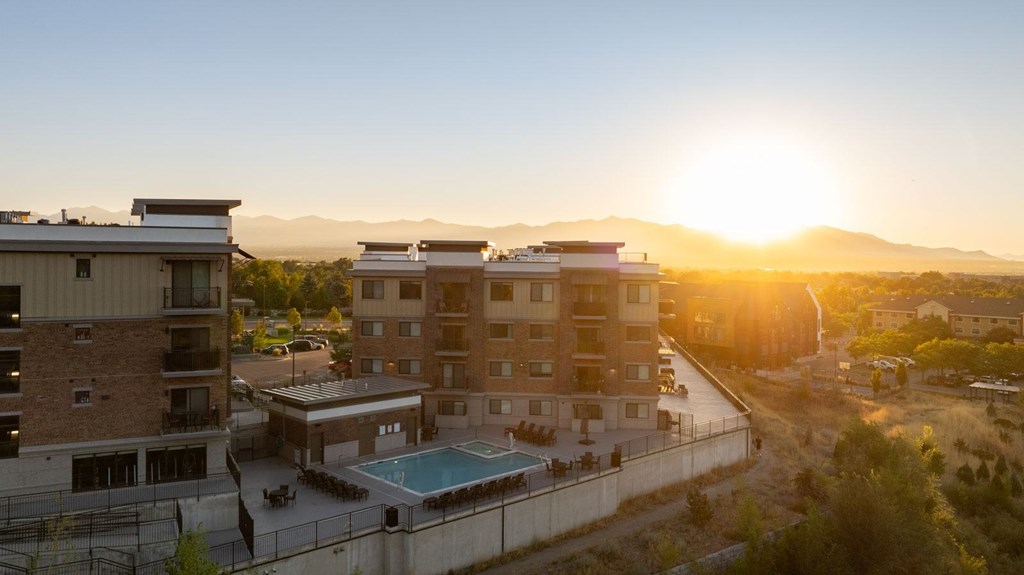 a building with a pool in front of a sunset