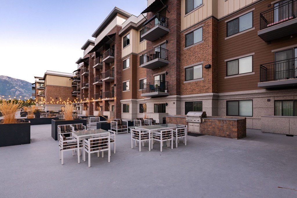 a patio with tables and chairs in front of an apartment building