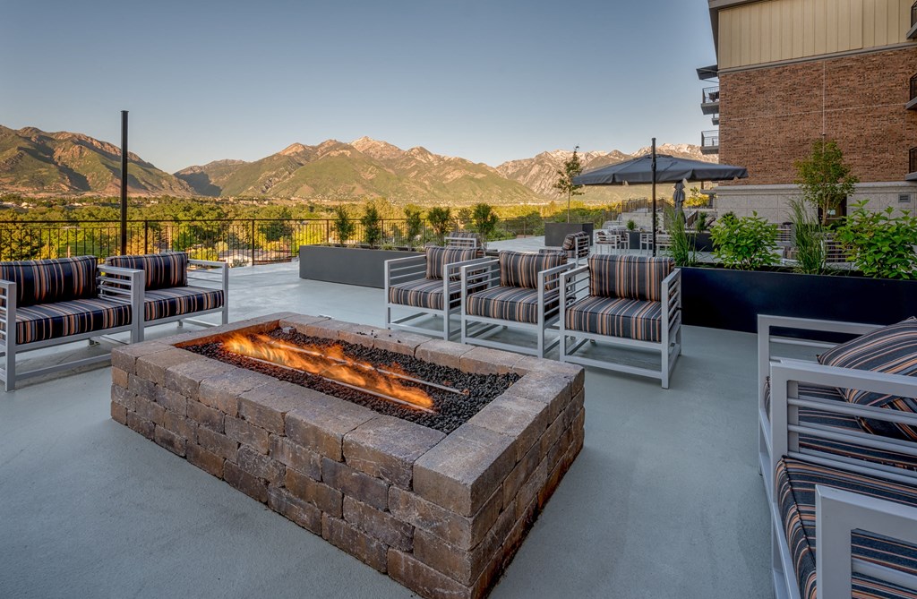 a fire pit on the patio of a building with chairs and tables