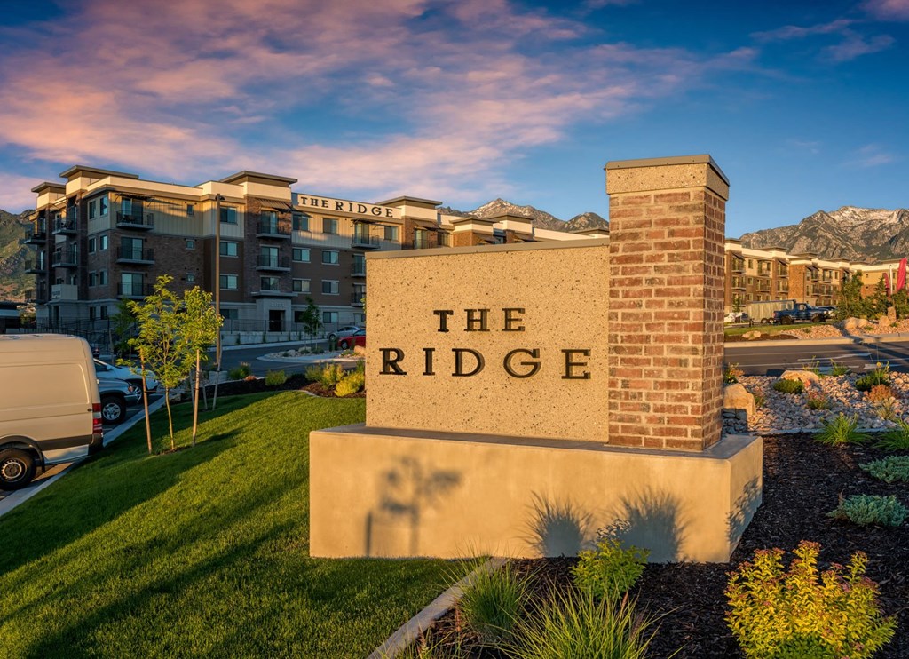 the ridge condominiums building sign in front of lawn and buildings