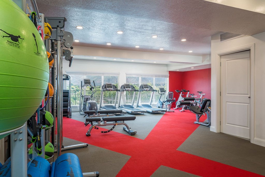 a gym with chairs and equipment in a room with windows
