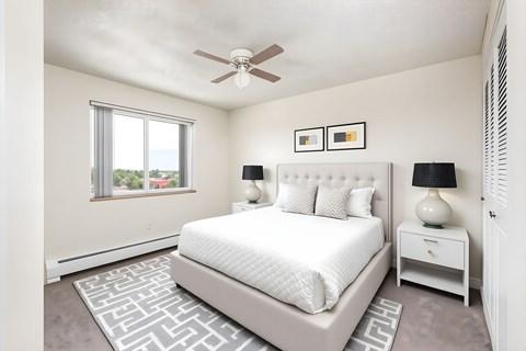 A bedroom with a large bed, a ceiling fan, and two lamps.