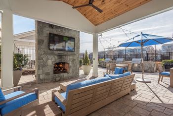 a covered patio with a stone fireplace and furniture