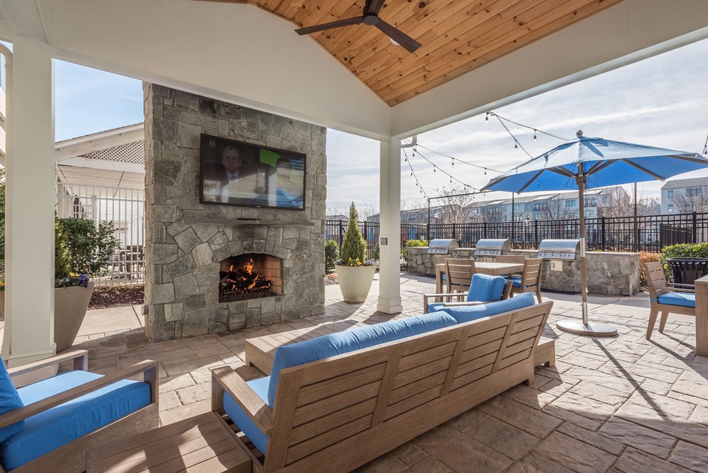 a covered patio with a stone fireplace and furniture