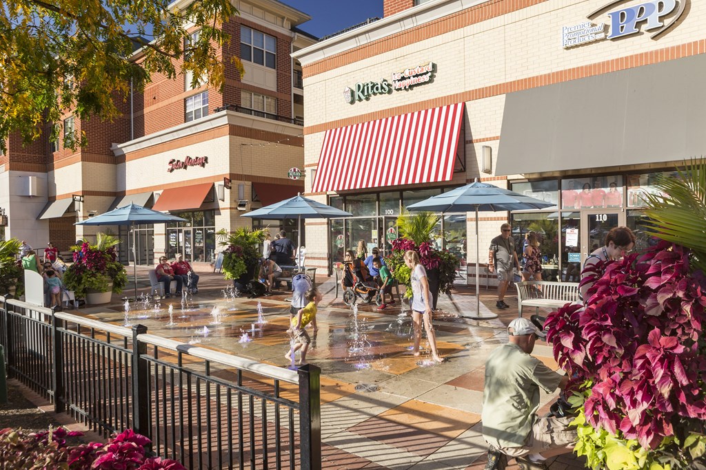 people playing in a water fountain outside of a shopping mall