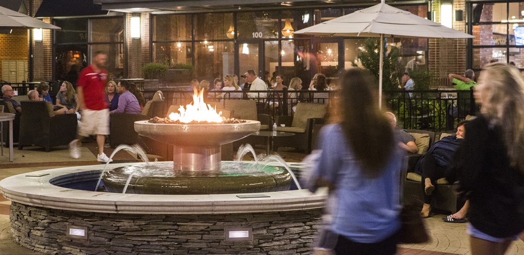 people walking around a fire fountain at night