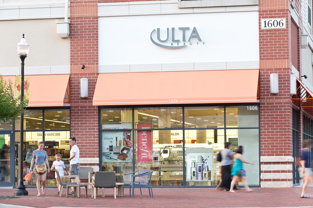 people walk past a store clothing on a city street