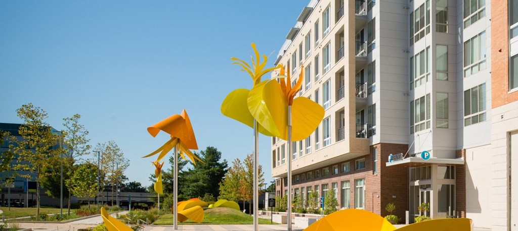 a city street with yellow sculptures in front of an apartment building at The Metropolitan Downtown Columbia, Maryland