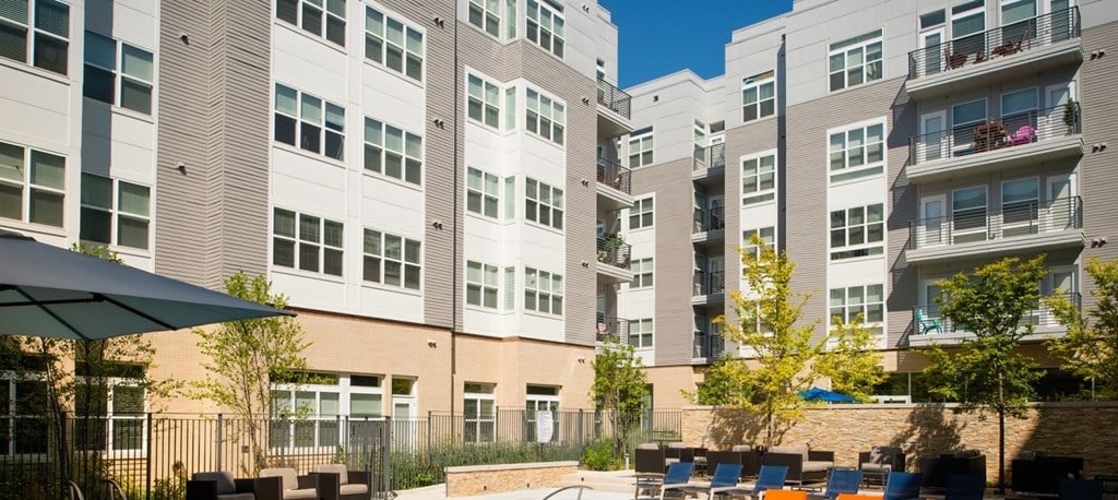 an outdoor patio with tables and chairs in front of an apartment building at The Metropolitan Downtown Columbia, Columbia, MD, 21044