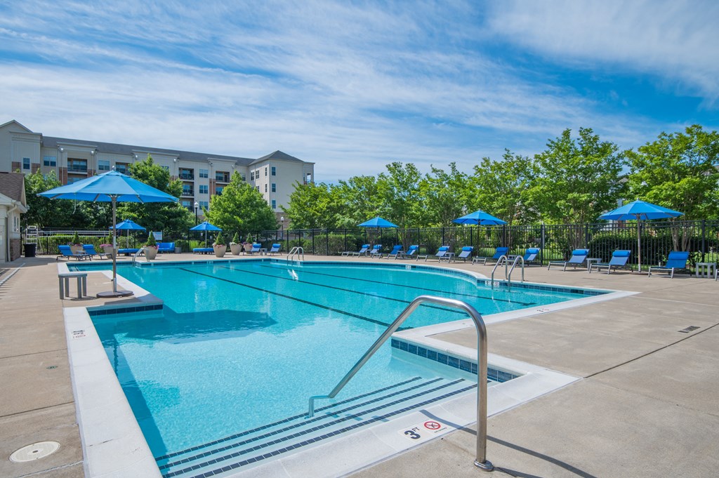 a swimming pool with blue umbrellas and a building in the background