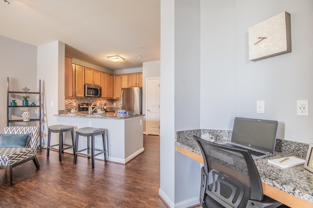 a kitchen and living room with a laptop computer on a desk