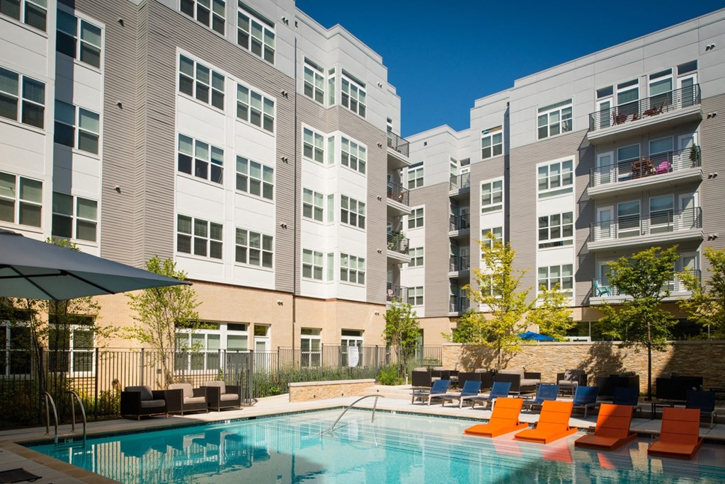 a swimming pool with orange chairs in front of an apartment building at The Metropolitan Downtown Columbia, Columbia, 21044