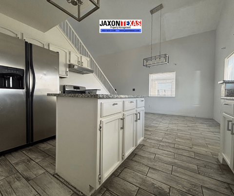 A kitchen with a refrigerator, cabinets, and a stove top oven.