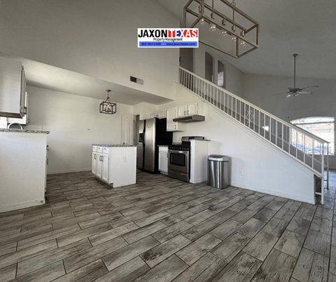 A kitchen with a wooden floor and a staircase.