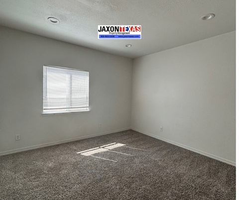 A room with a carpet floor and a window with blinds.