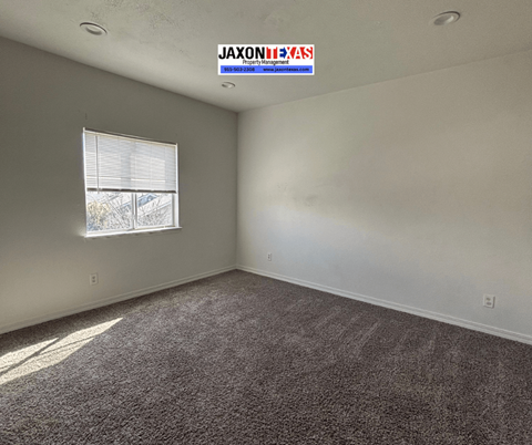 A room with a carpeted floor and a window letting in sunlight.