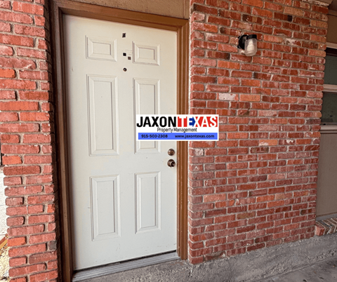 A white door with a sign that says "Jaxonixas Property Management" on a brick wall.