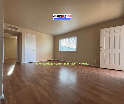 Empty room with wooden floors and white doors.