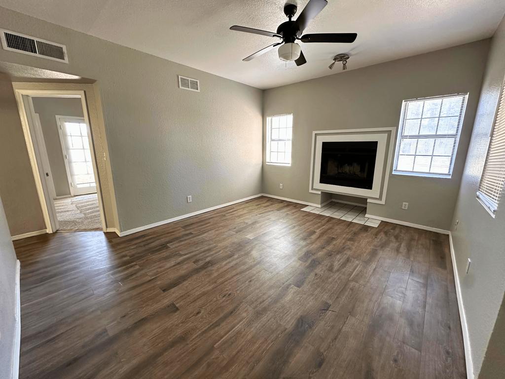 A room with a ceiling fan and a flat screen TV.