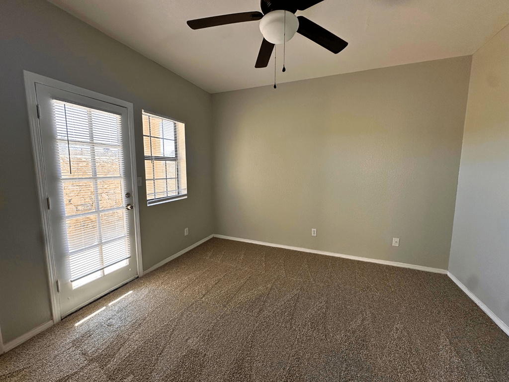 A room with a ceiling fan and carpeted floor.