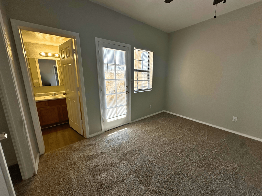 A room with a carpeted floor, a mirror, and a window.