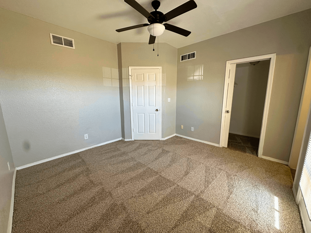 A room with a ceiling fan and carpeted floor.