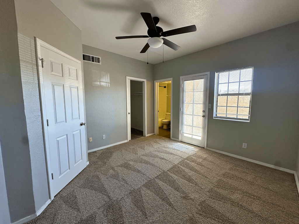 A room with a ceiling fan and carpeted floor.