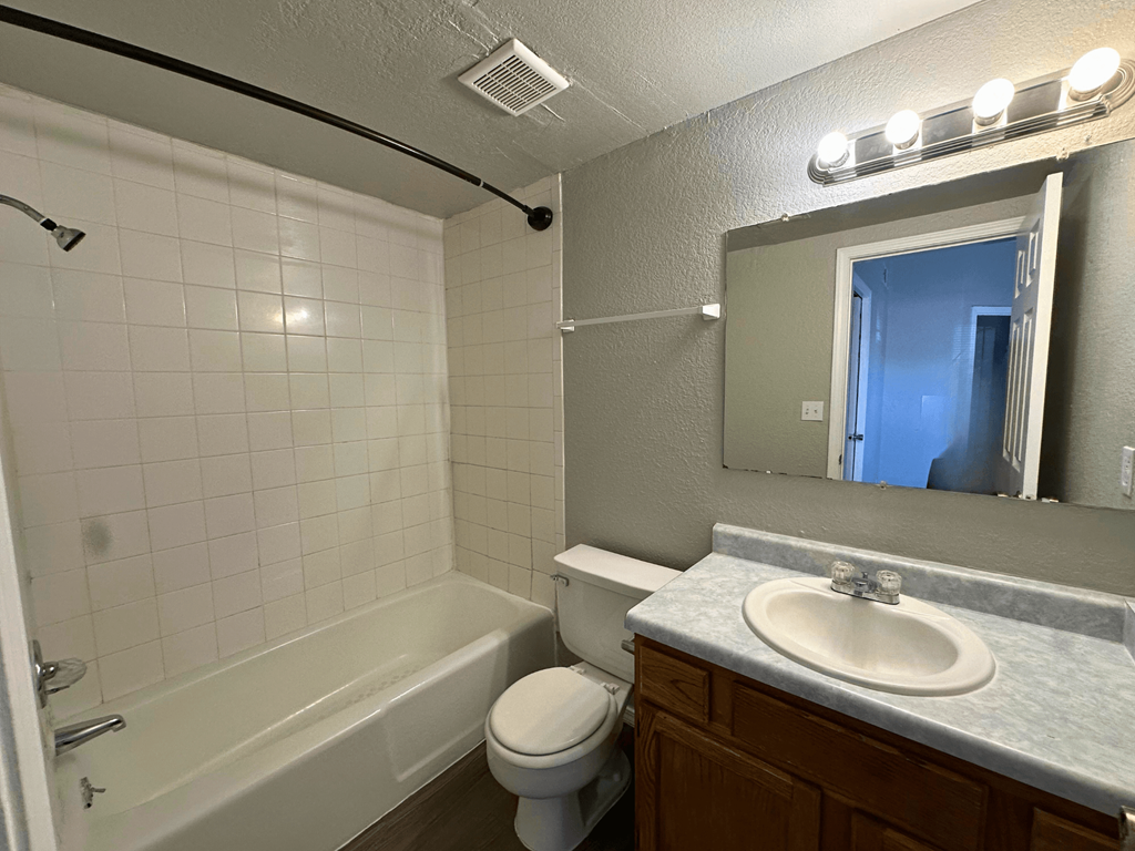 A white tiled bathroom with a sink, toilet, and bathtub.