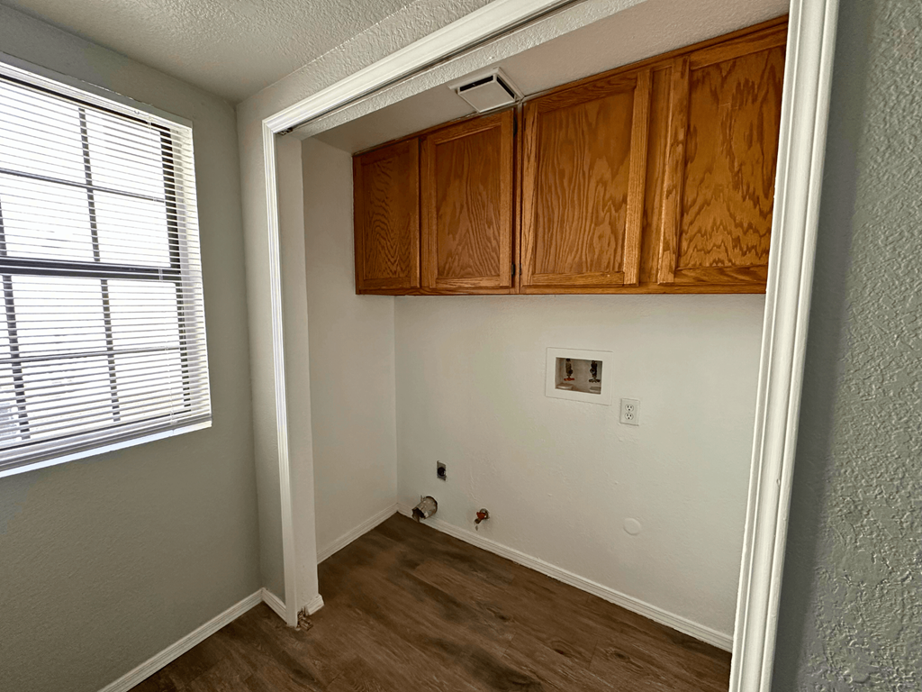 A room with wooden cabinets and a window with blinds.